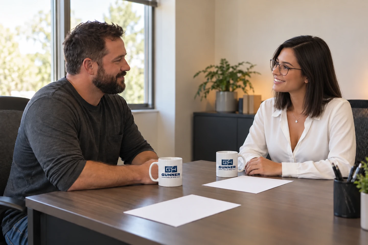 Driver candidate and recruiter speaking across a table with two Gunner Holding mugs